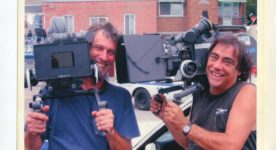 Le directeur photo Jean-Pierre St-Louis et le cinéaste Robert Morin sur un plateau de tournage avec leur caméra à l'épaule.